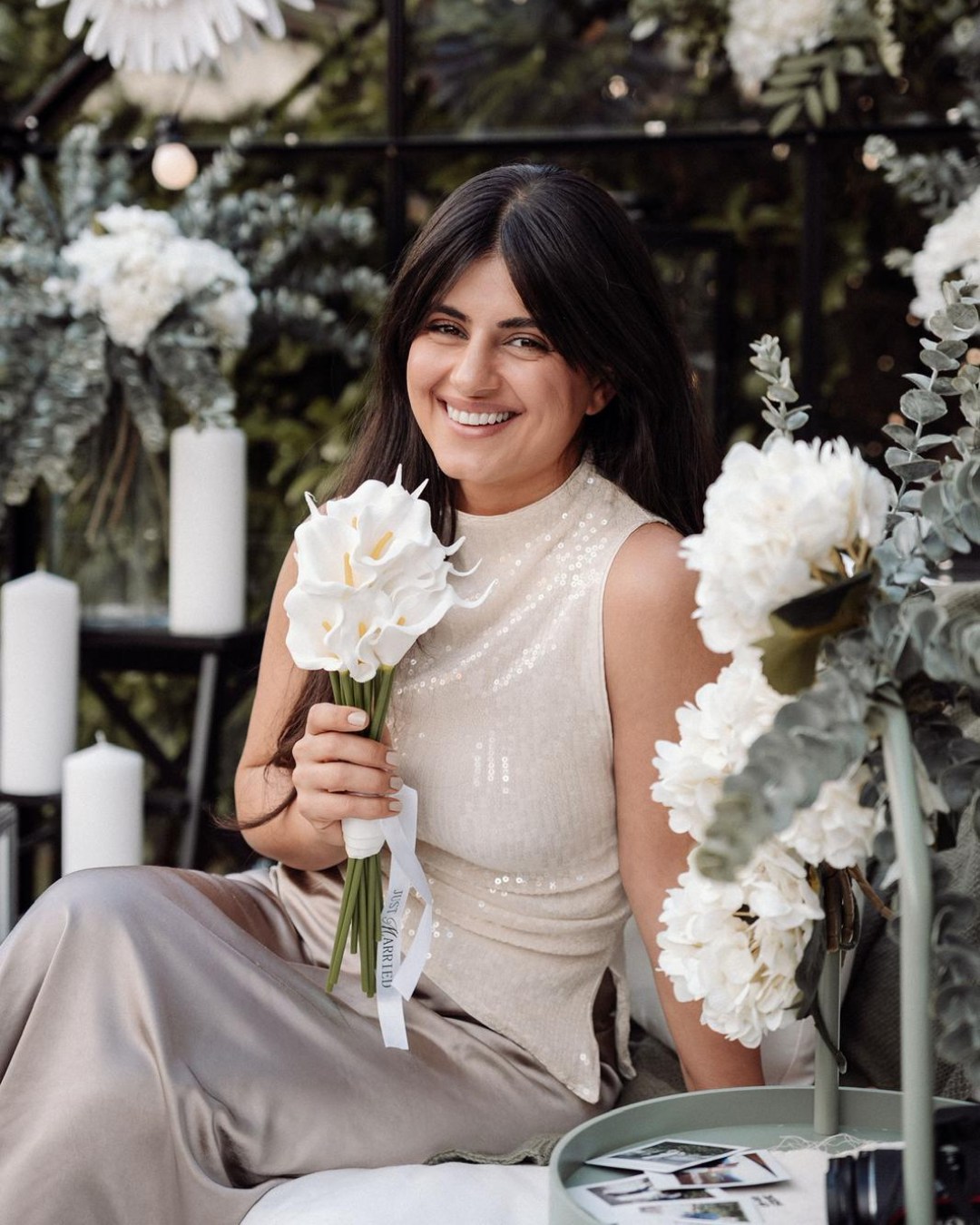 Deli Ibrahim Wedding Photography sitzt in einem Blumengarten mit weißen Rosen.